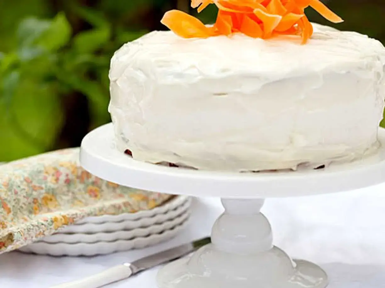 En saftig glutenfri morotskaka med vit frosting och strimlade morötter som dekoration. Perfekt för fikat!
