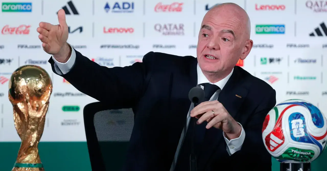 Prezydent FIFA, Gianni Infantino, gestykuluje podczas konferencji prasowej obok Pucharu Świata i piłki.