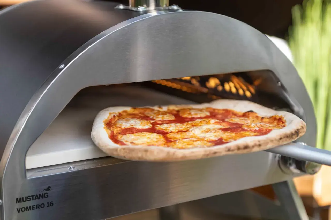 En pizza med tomatsås och ost bakas i en ugn på en pizzasten eller pizzastål.