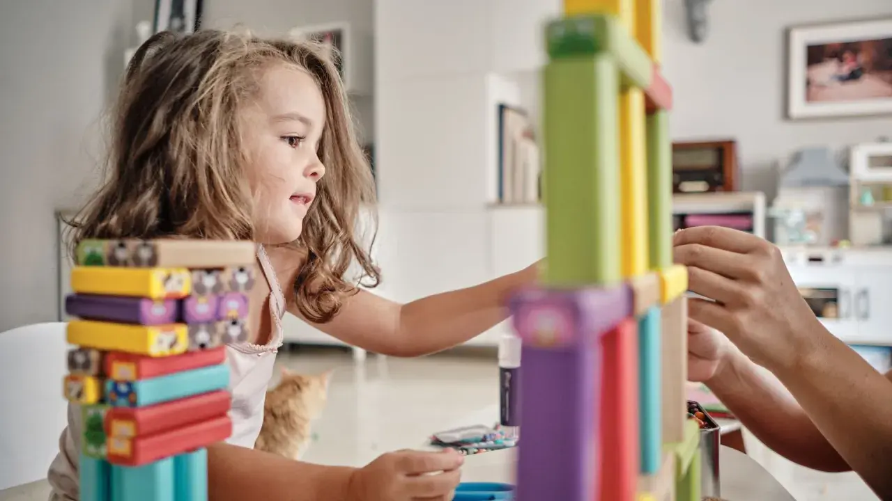 Niña concentrada construyendo con bloques de colores, disfrutando de juegos de habilidad para niños.