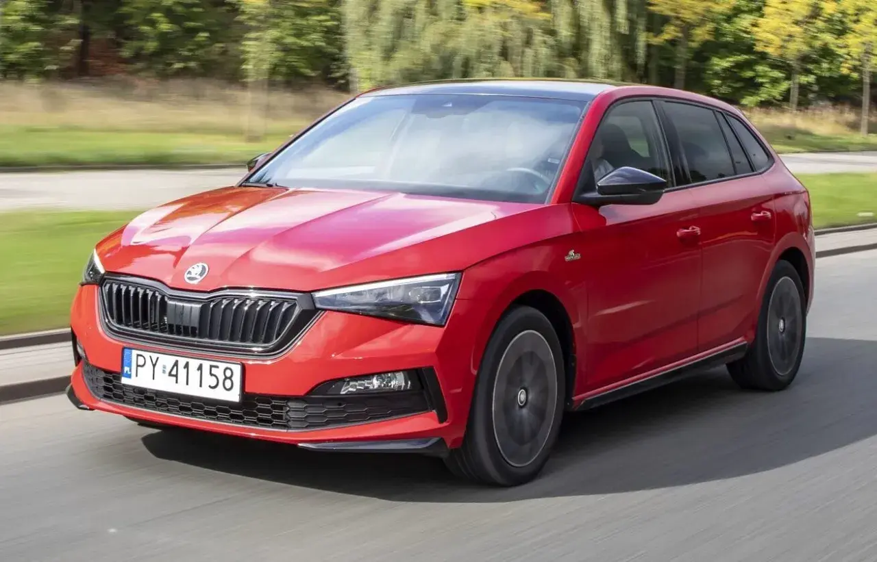 Czerwona Skoda Scala Monte Carlo pędzi po drodze, błyszcząc w słońcu.