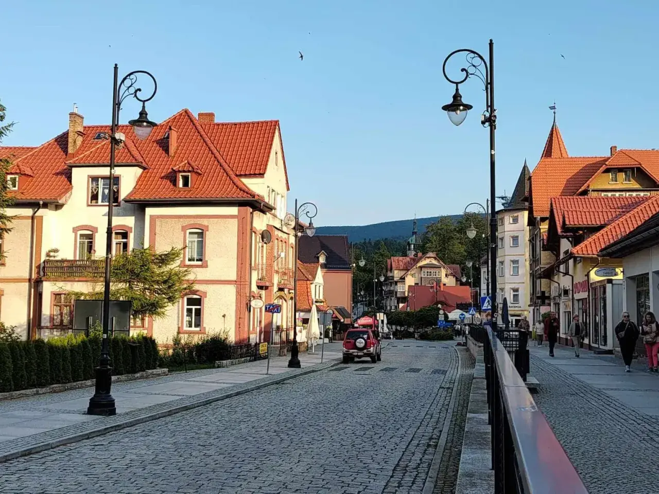 Urokliwa ulica w Świeradowie-Zdroju, z kamienną nawierzchnią i zabytkowymi kamienicami. Idealne miejsce na spacer po uzdrowisku, które przypomina krajobraz z Jeleniej Góry.