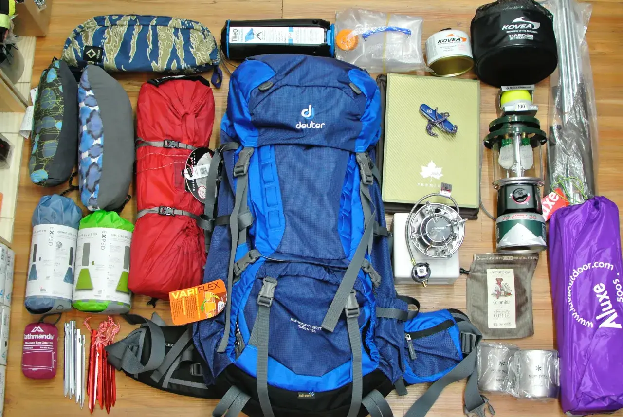 Alles, was man braucht für Camping: Rucksack, Schlafsäcke, Isomatten, Kocher, Lampe, Zeltstangen, Tasse und mehr.