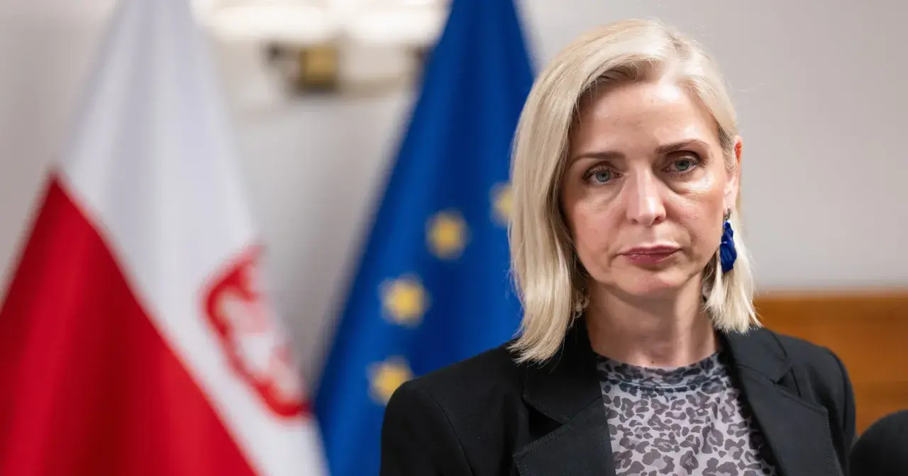 Znana posłanka KO zrezygnowała z mandatu dla kariery w biznesie prywatnym. Na zdjęciu kobieta z blond włosami, w czarnej marynarce, na tle flag Polski i UE.