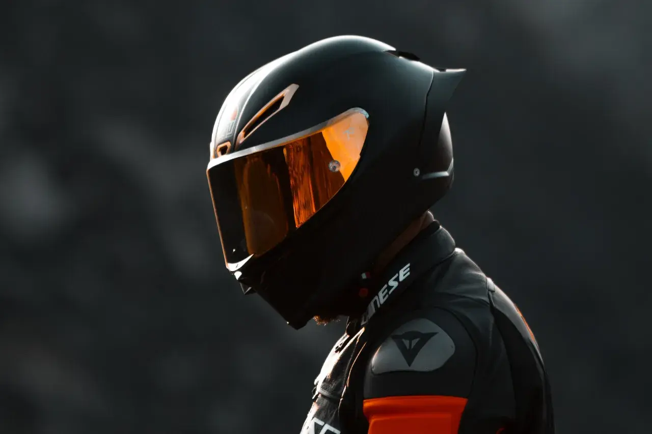 Casco da moto sportivo con visiera arancione riflettente, uno dei tanti tipi di casco per la sicurezza in pista.