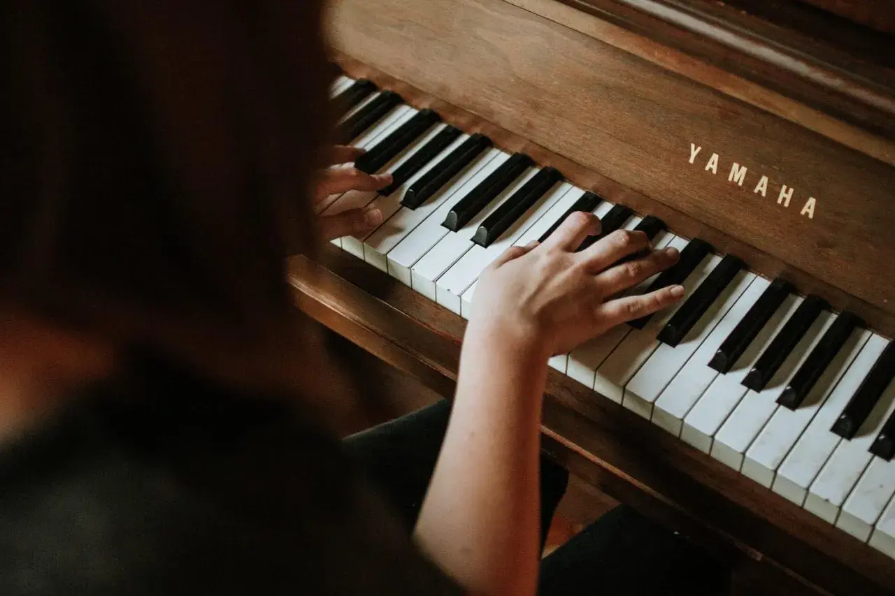 Dłonie na klawiaturze pianina Yamaha. Rozpoczyna się nauka gry na pianinie online, odkrywanie melodii.