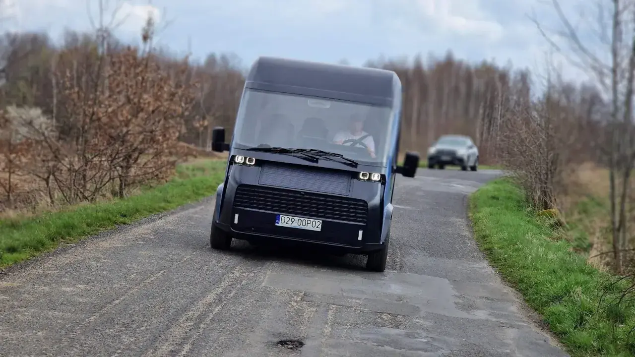 Nowoczesny polski samochód elektryczny przemierza wiejską drogę.