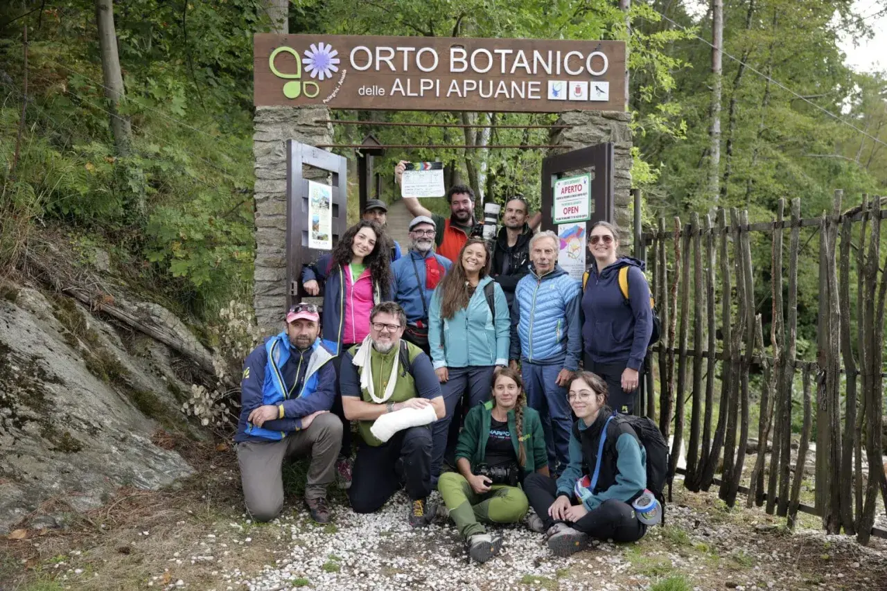Gruppo di escursionisti posa davanti all'Orto Botanico delle Alpi Apuane. Un uomo tiene in mano una ciak.