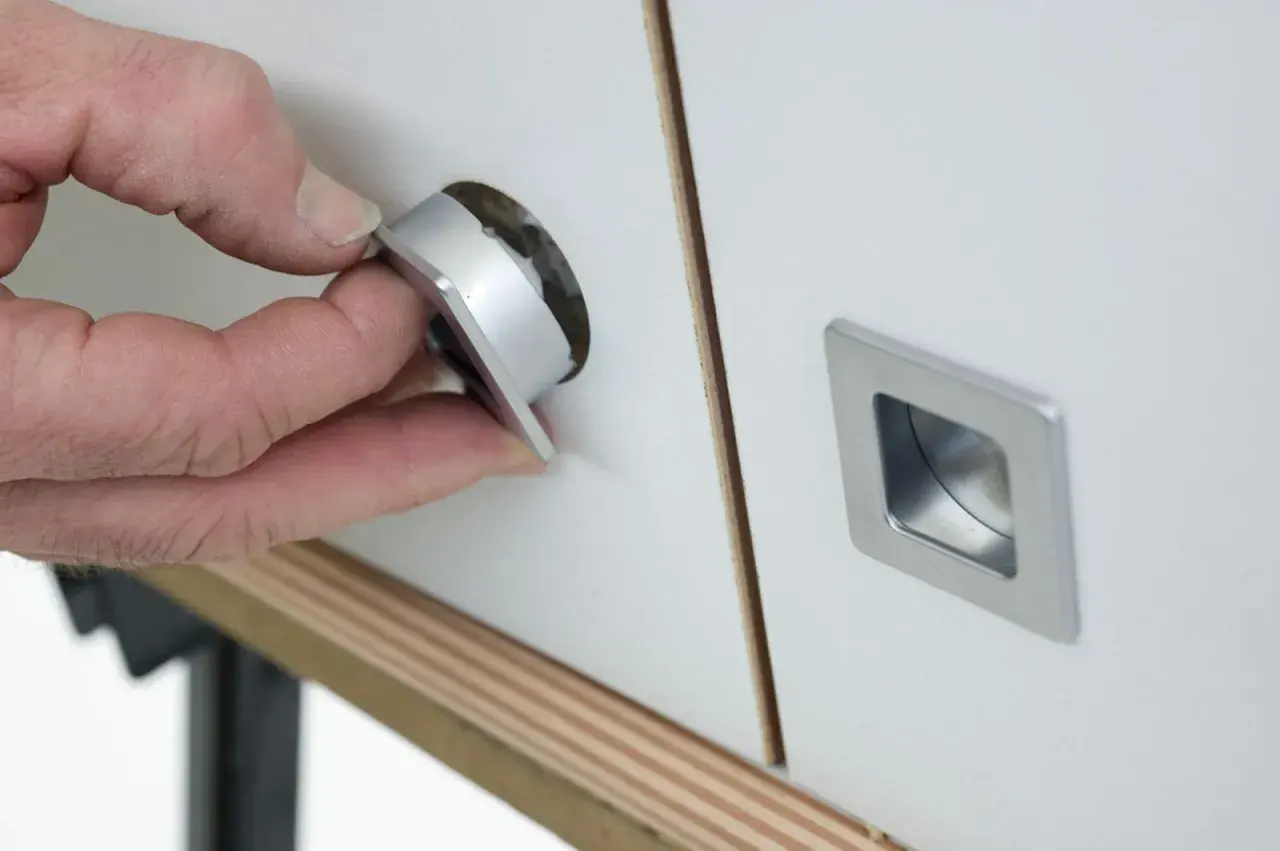Mano insertando un tirador moderno en un mueble, renovando su aspecto. Ideal para cambiar tiradores mueble antiguo.