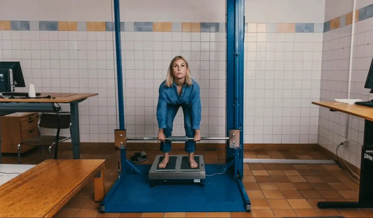 Kvinna gör sig redo för ett styrketest, kanske för att se om hon klarar "kan jag bli polis test". Hon håller i en skivstång.
