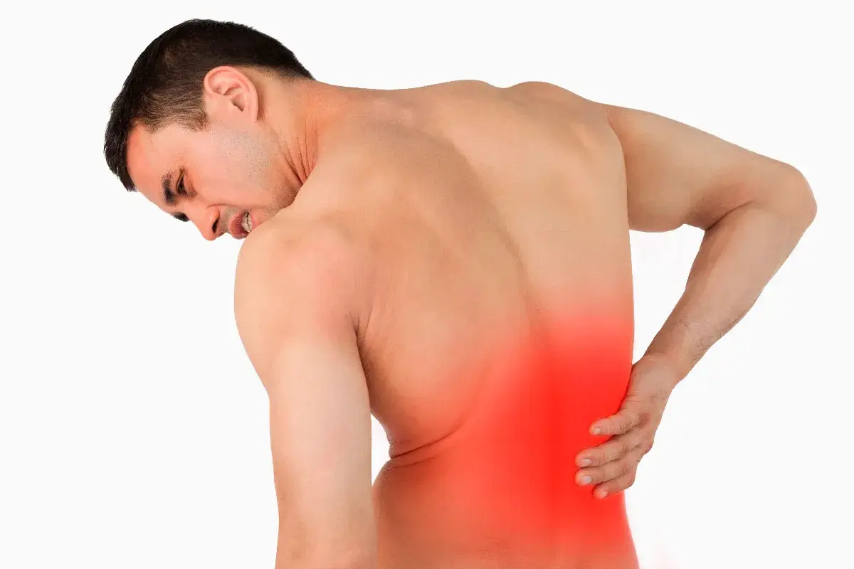 Hombre con dolor lumbar izquierdo, con la mano en la zona afectada y expresión de sufrimiento.