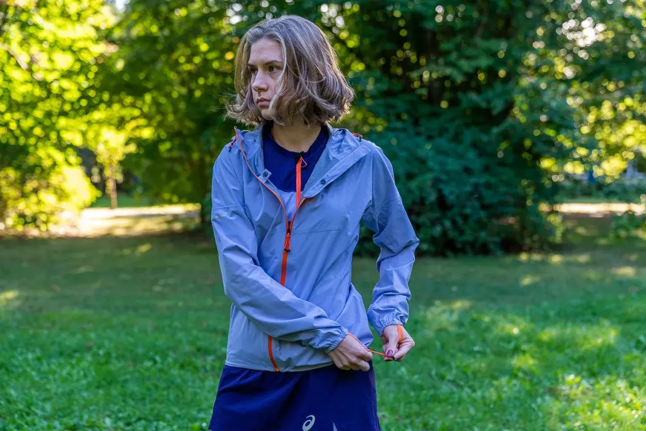 Kobieta w niebieskiej kurtce sportowej z pomarańczowymi zamkami. Taka membrana 10000 co to znaczy? To dobra ochrona przed deszczem i wiatrem podczas biegania.