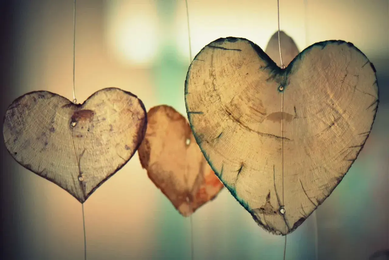 Holzherzen hängen an dünnen Fäden. Sie erinnern an die wahre agape bedeutung: bedingungslose Liebe, die wächst und Bestand hat.