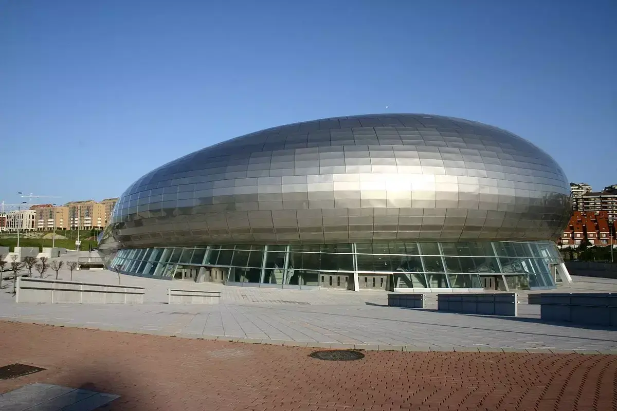 El moderno Palacio de Deportes Santander, con su diseño futurista y su cubierta plateada, se alza bajo un cielo azul.