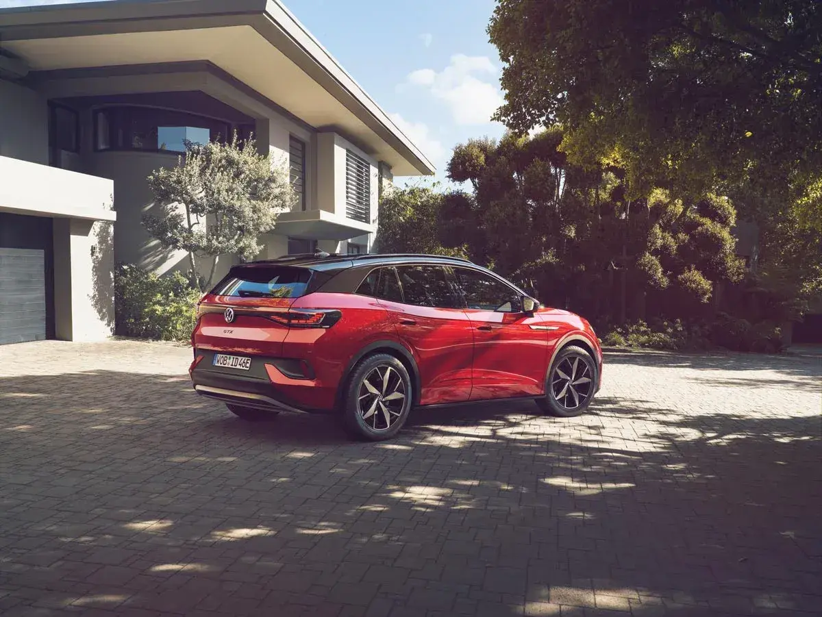 Röd elbil parkerad på uppfart framför modernt hus. En dag för att fundera på hur många elbilar som finns i Sverige.