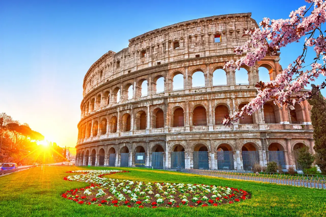 Colosseo illuminato dal sole, con fiori primaverili. Ideale per un soggiorno di costo metro Roma 2 giorni.