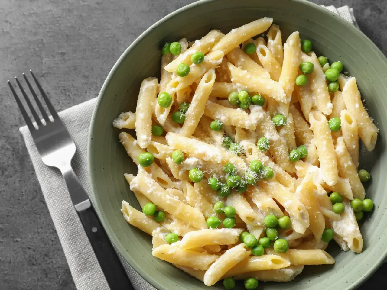 Penne z kremowym sosem i zielonym groszkiem, posypane parmezanem. Idealne danie, gdy masz ochotę na pyszny makaron z groszkiem.