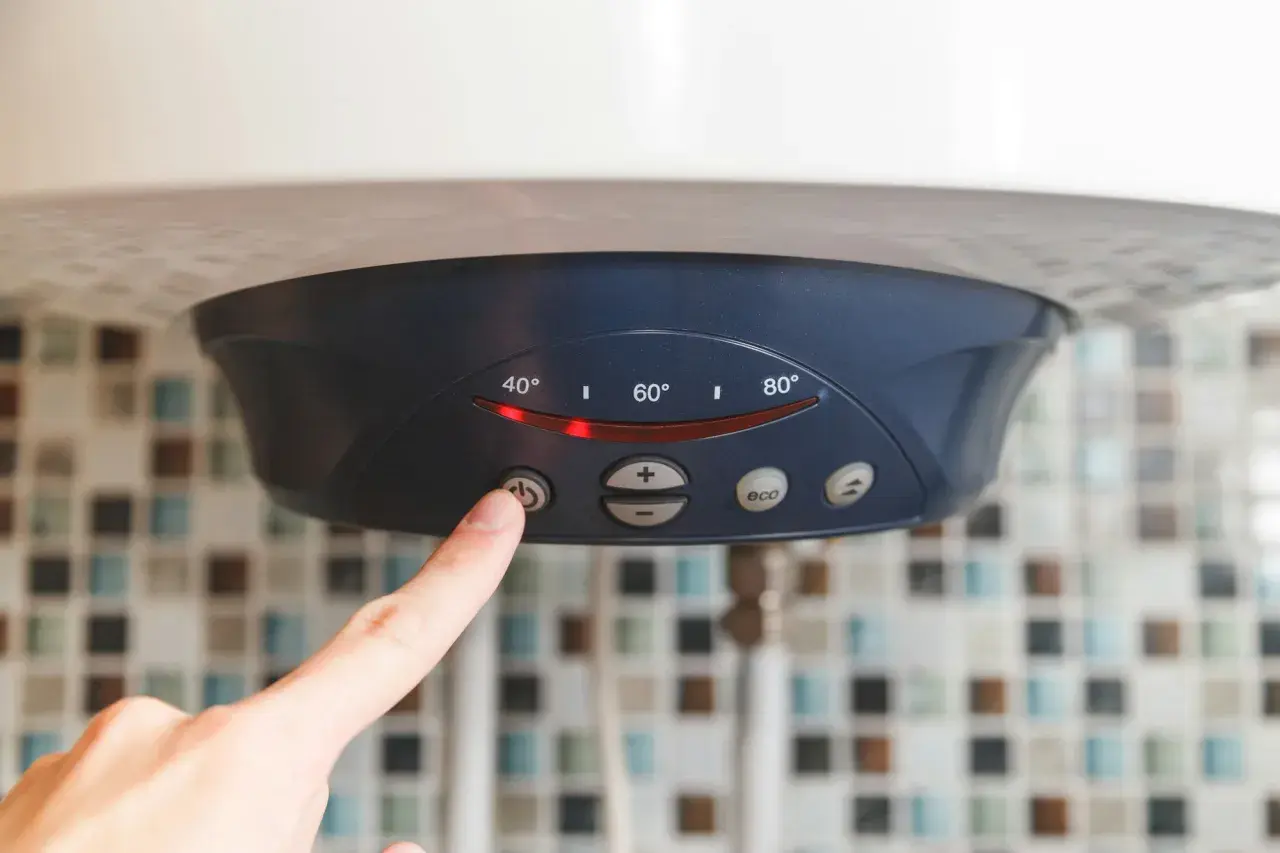 Palec naciska przycisk na bojlerze elektrycznym 60l, pokazując ustawienia temperatury. Zastanawiasz się, ile prądu zużywa bojler elektryczny 60l?
