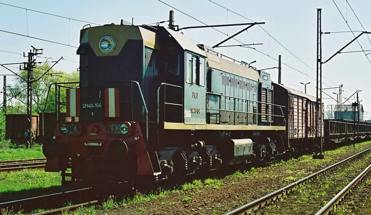 Lokomotywa SM48-104 z wagonami towarowymi na torach.