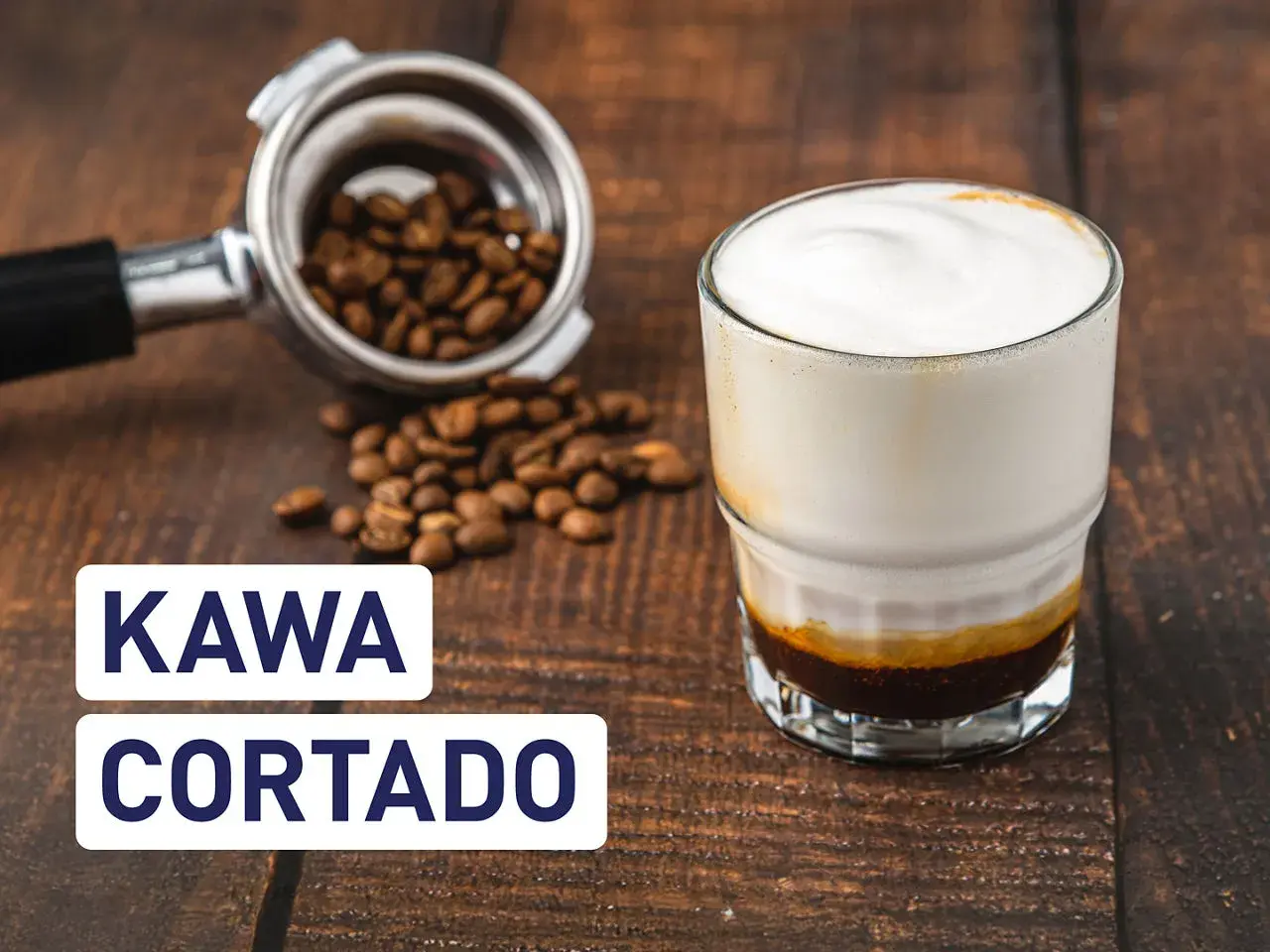 Kawa cortado z mleczną pianką, obok portafiltr z ziarnami kawy. Idealna na poranek.