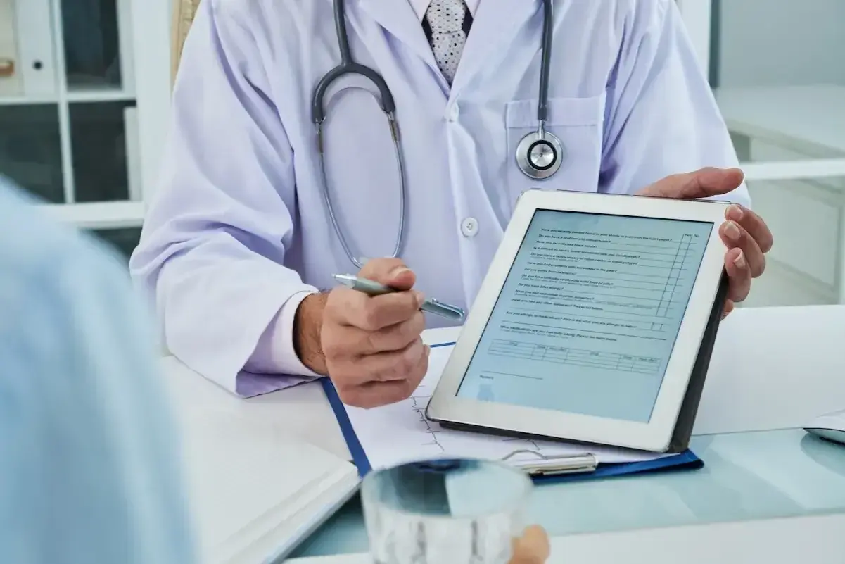 Medico con stetoscopio mostra un modulo su tablet, forse per una nuova unità di degenza.