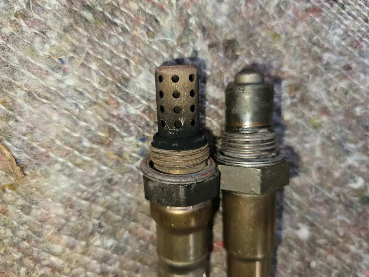 Zwei Lambdasonden, eine mit verrußtem Schutzgitter, möglicherweise Ursache für DTC P0420 bei Ford.
