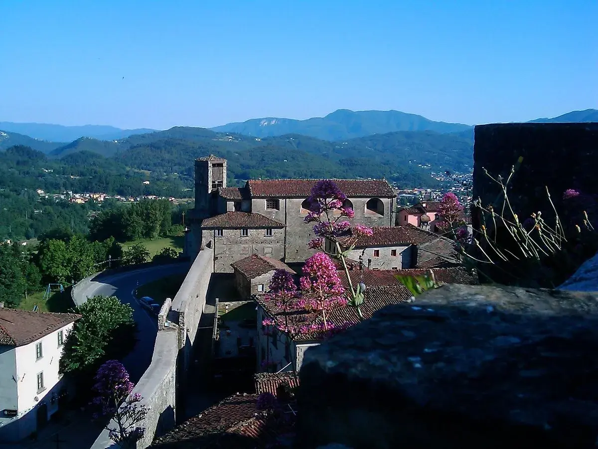 Panoramica di Castiglione di Garfagnana con il suo castello, le case con i tetti rossi e le montagne verdi sullo sfondo.
