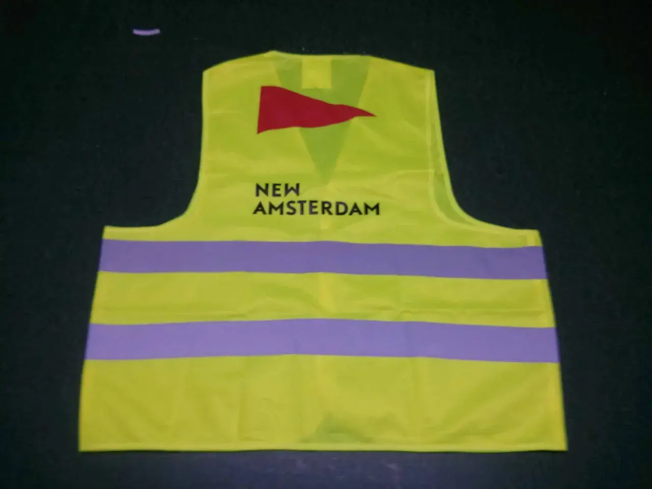 Kamizelka odblaskowa w kolorze limonkowym z napisem "NEW AMSTERDAM" i czerwonym logo. To przykład znakowania odzieży.