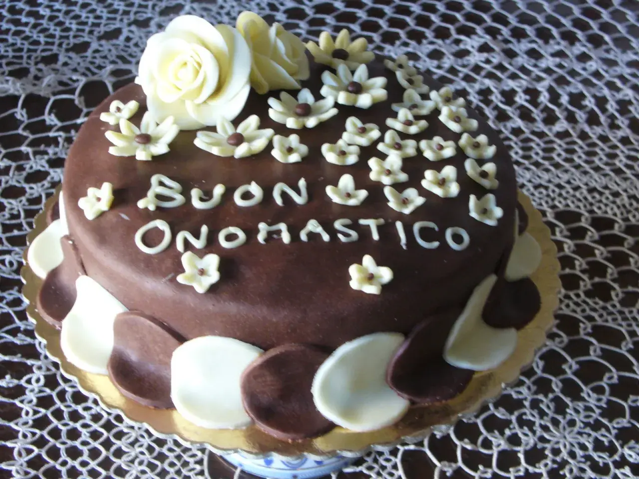 Torta al cioccolato con decorazioni in pasta di zucchero, un augurio speciale: "Buon Onomastico" per un uomo.
