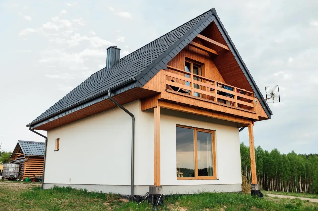 Nowoczesny dom kanadyjski, białe ściany, drewniana weranda i dach. Projekty domów tego typu są popularne.