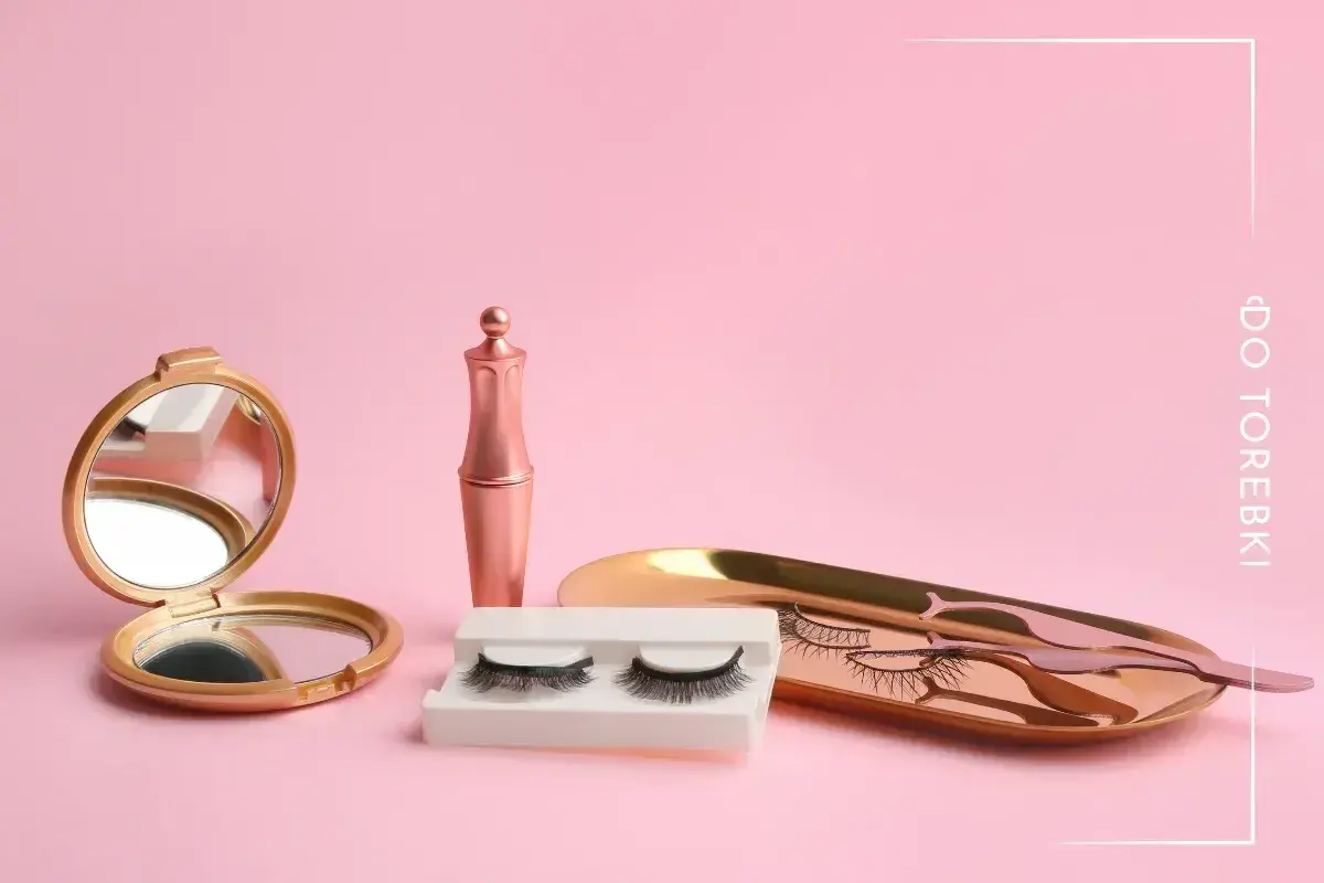 Zestaw do rzęs magnetycznych: lusterko, eyeliner, rzęsy i pęseta na różowym tle.