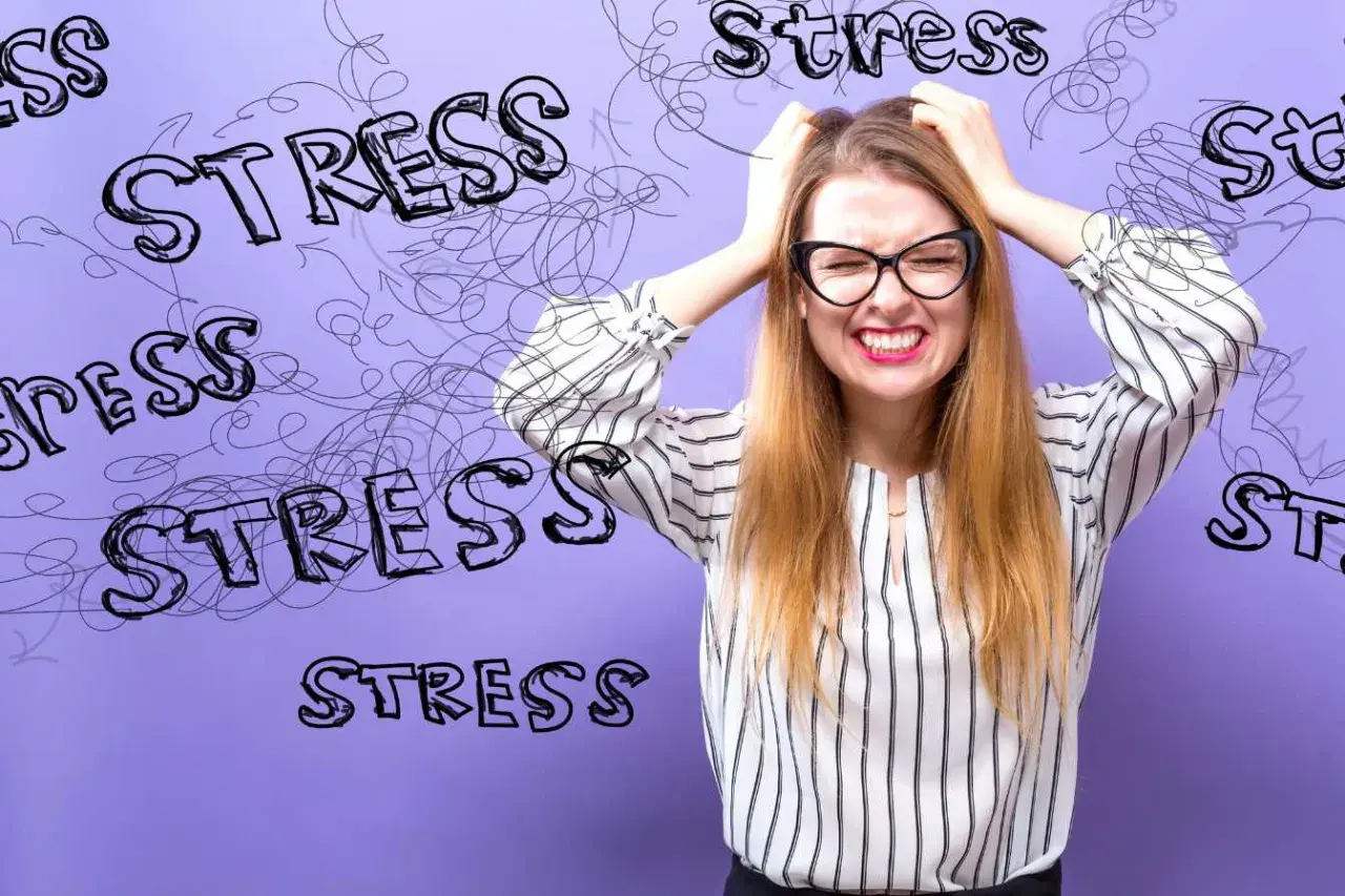 En kvinna med glasögon drar sig i håret, ansiktet förvridet av ansträngning. Orden "stress" är utspridda runt henne, som en visuell representation av hennes arytmi stress.