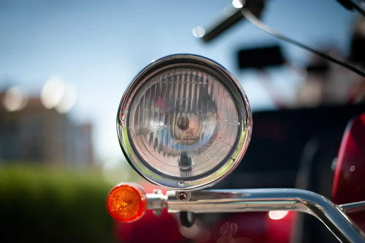Chromowany reflektor i pomarańczowy kierunkowskaz motoroweru. Czy motorower musi mieć kierunkowskazy? Tak, dla bezpieczeństwa.