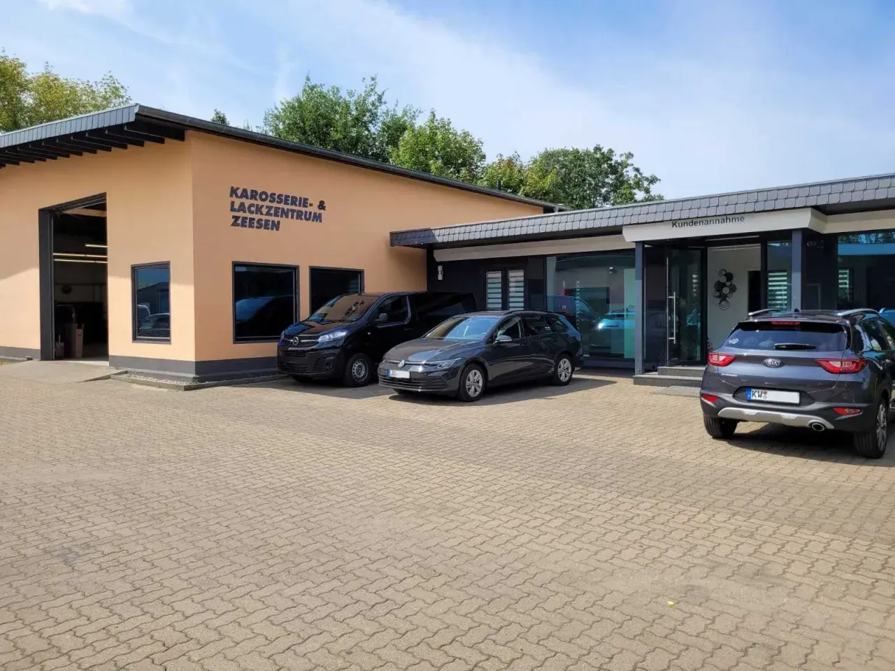 Gebäude des Karosserie- & Lackzentrums Zeesen mit Autos davor.