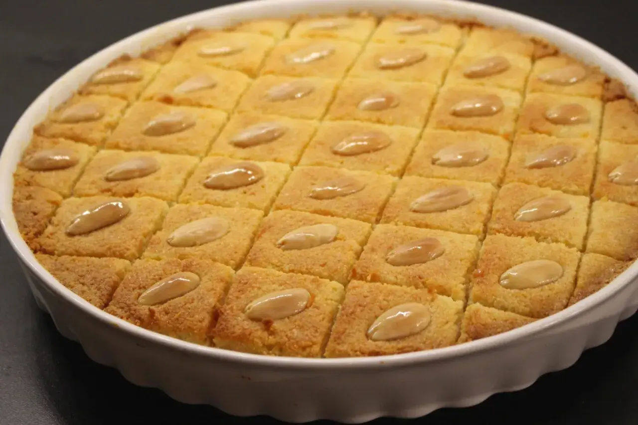 En gyllene basbousa, skuren i rutor och toppad med mandlar. Perfekt för ett enkelt basbousa recept.
