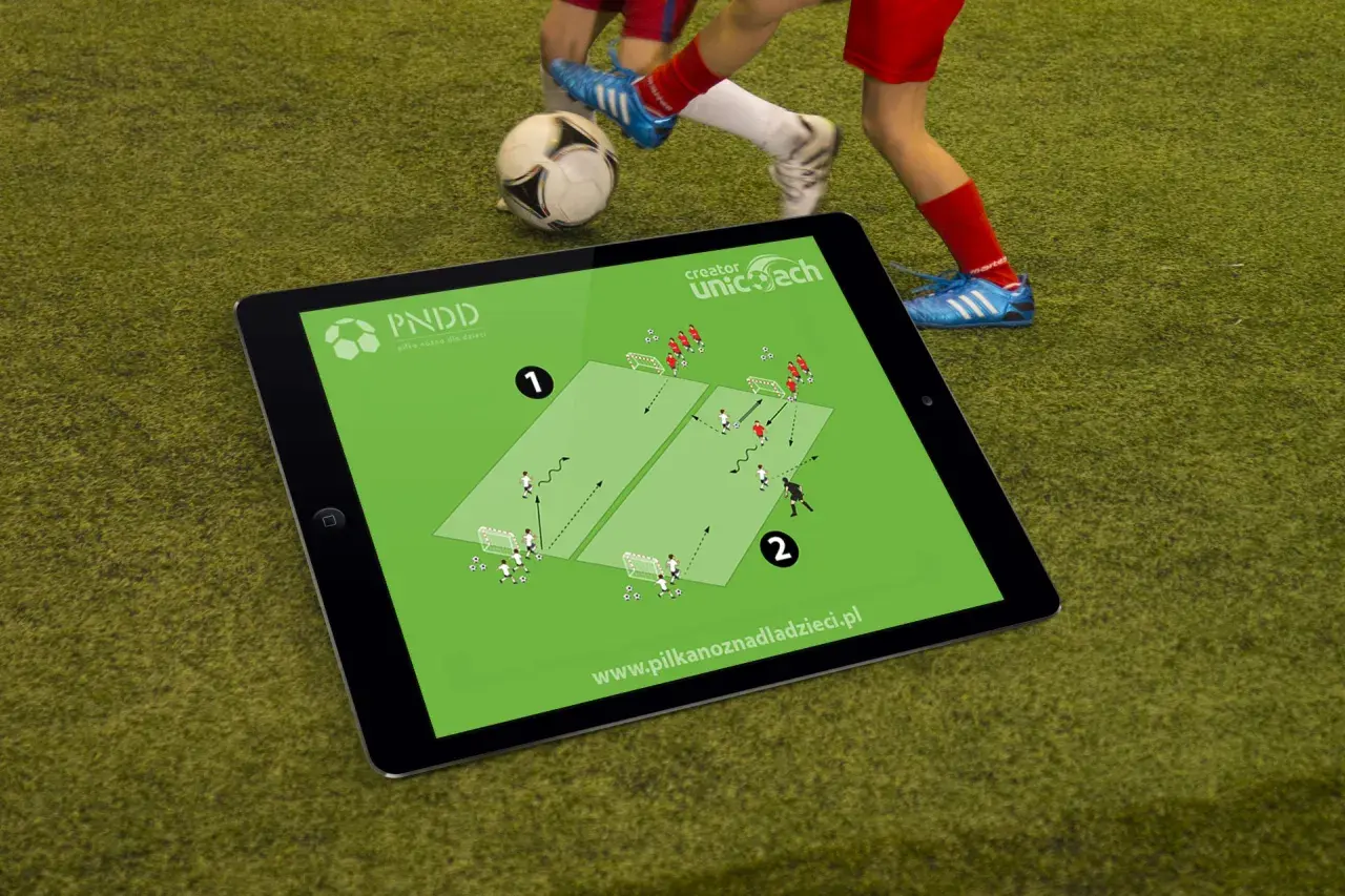 Tablet z planem treningowym do piłki nożnej na 2 osoby. Dzieci ćwiczą na boisku.