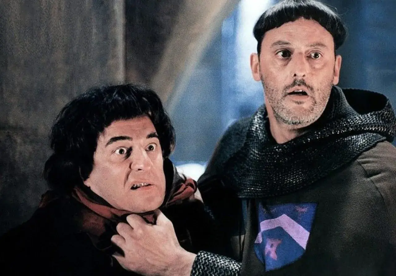 Goście, goście! Obsada filmu w średniowiecznych strojach, jeden z nich groźnie patrzy, drugi ma rękę na jego szyi.