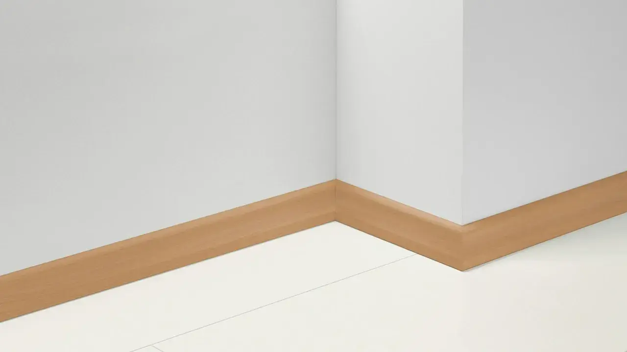 Angolo di una stanza con battiscopa in PVC effetto legno. Impara come tagliare battiscopa PVC per un'installazione perfetta.