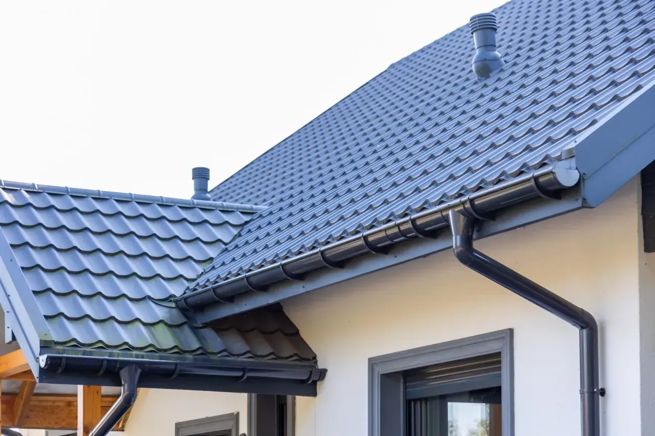 Szary dach z dachówki ceramicznej, idealny do obliczenia dachówka ceramiczna cena za m2. System rynnowy odprowadza wodę.