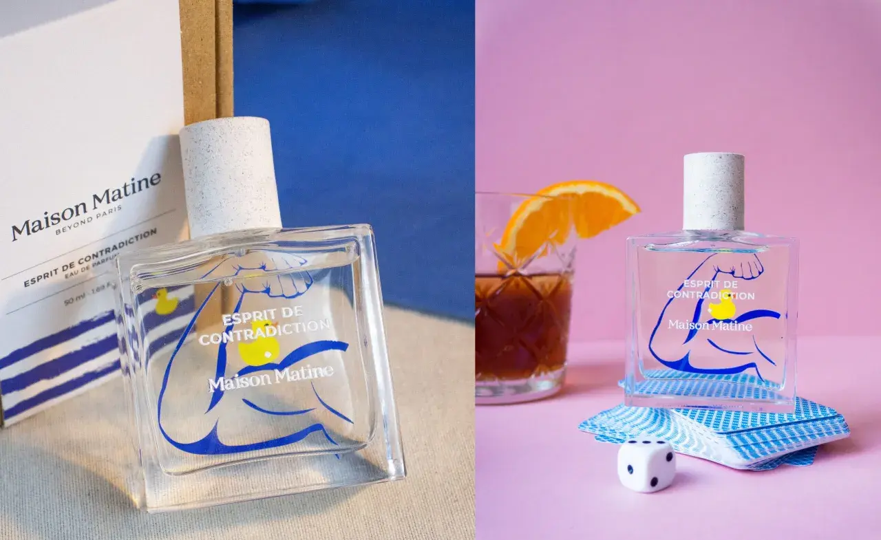 Perfumy Maison Matine Esprit de Contradiction w szklanej butelce z niebieskim wzorem. Obok kostka do gry i talia kart.