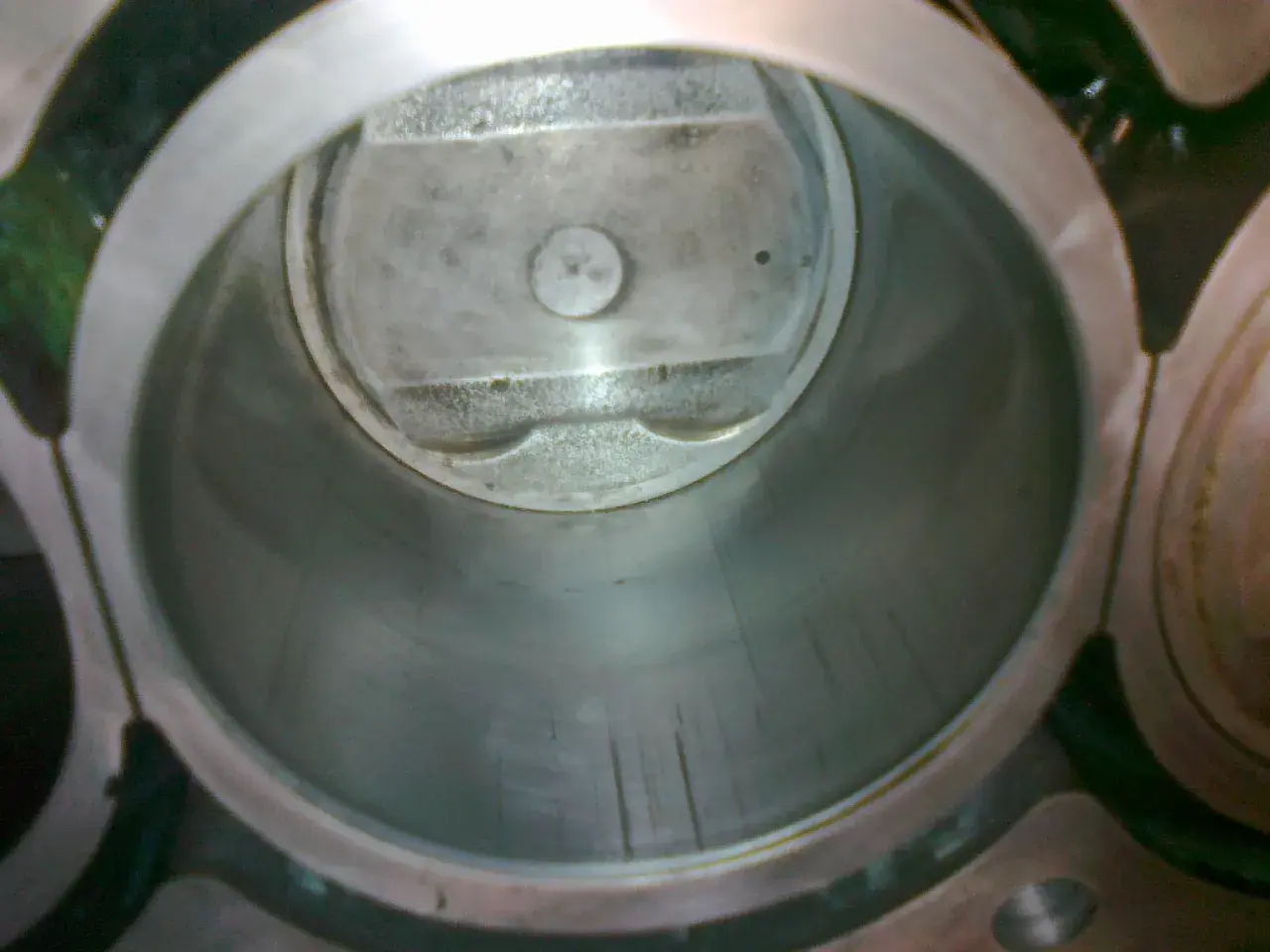 Wnętrze cylindra silnika z widocznym tłokiem. Widać ślady zużycia na ściankach, sugerujące dopuszczalny luz tłoka w cylindrze.