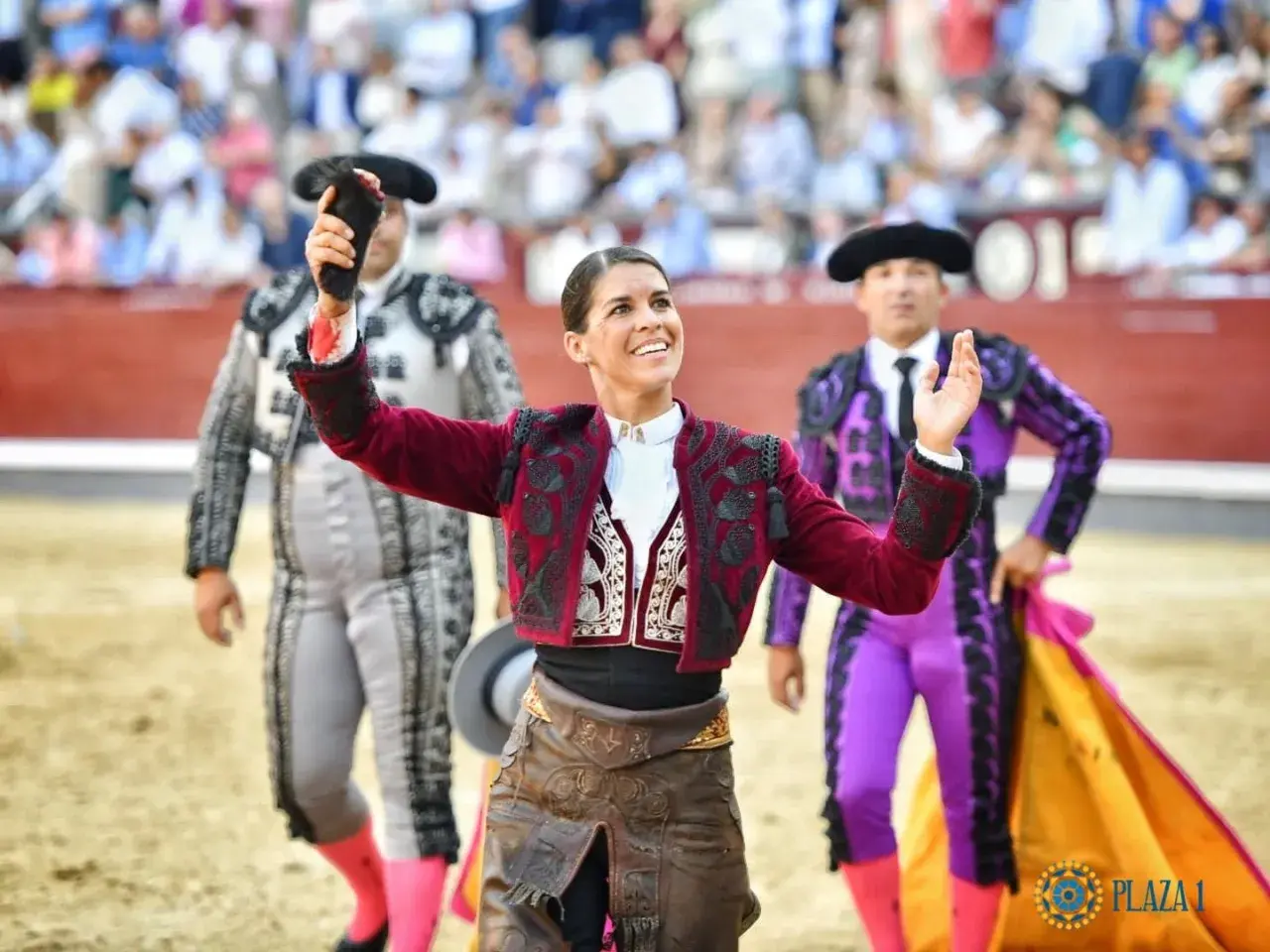Mujeres de toreros famosos, con trajes de luces, saludan al público en la plaza de toros.