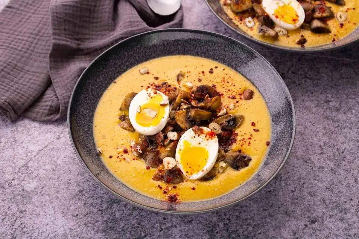 Velouté de patate douce garni de champignons, de noisettes et d'un œuf mollet.