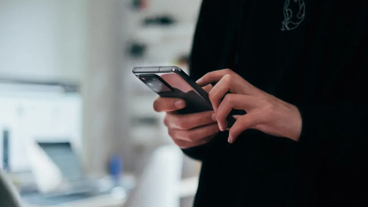 Dłonie trzymające nowoczesny smartfon, widok z bliska.