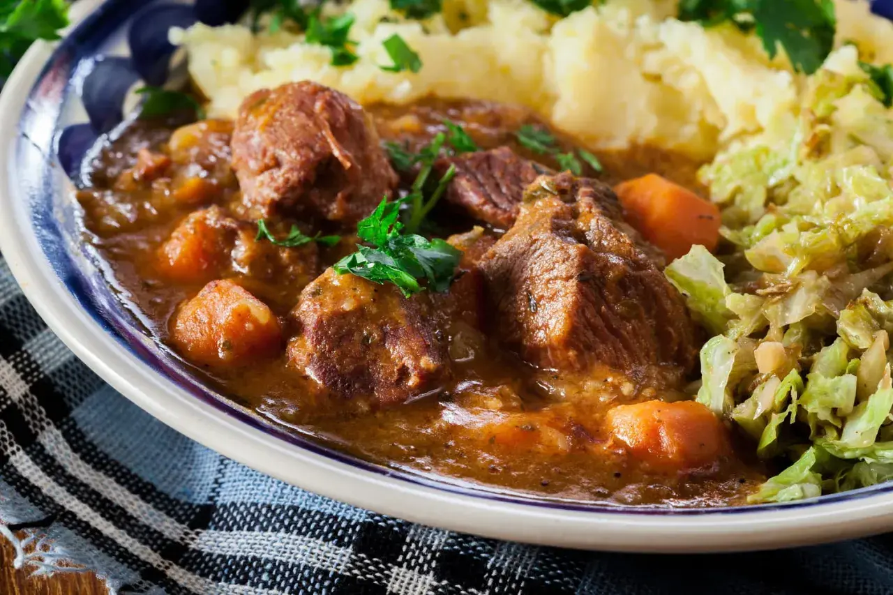 Un plat réconfortant de navarin d'agneau, avec des morceaux de viande tendres, des carottes et une sauce savoureuse, servi avec de la purée et du chou. Une recette parfaite pour un repas familial.