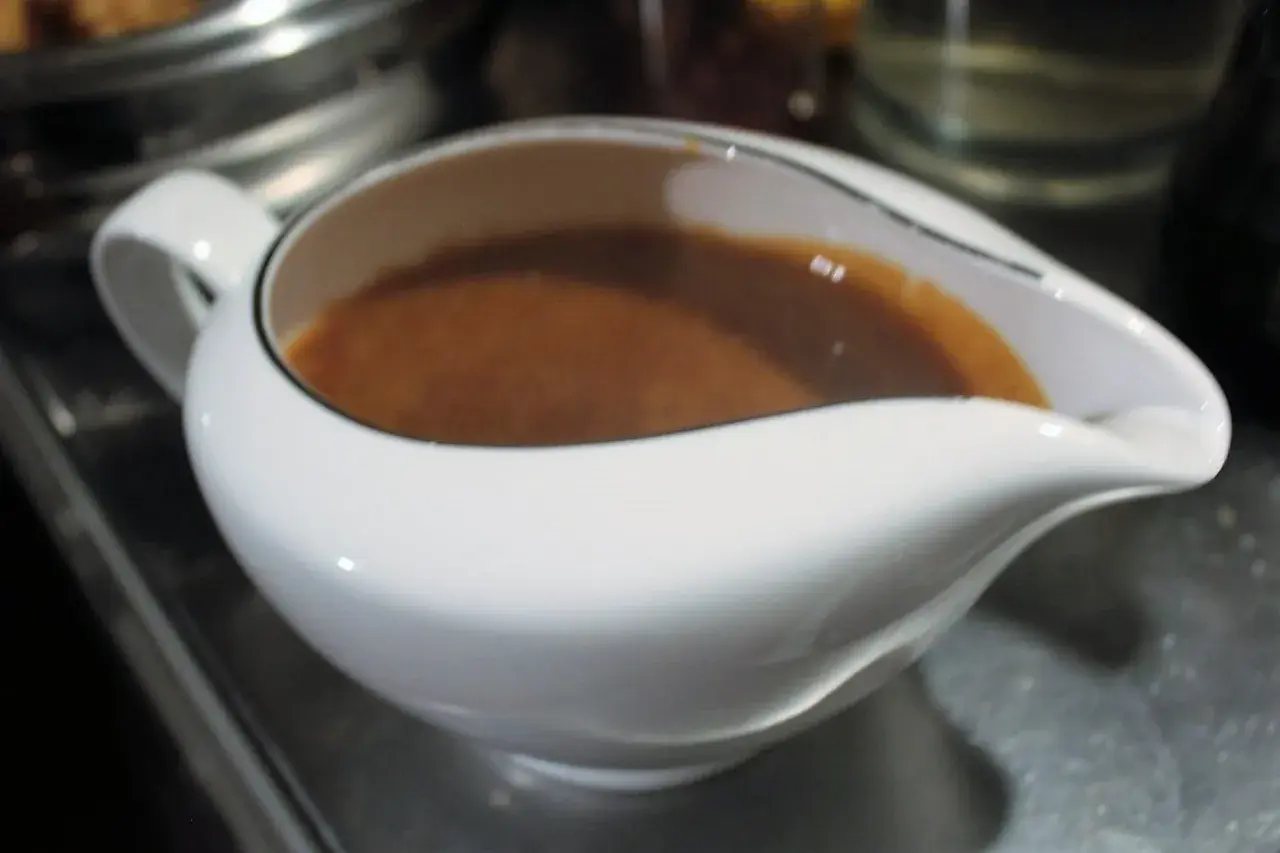 Eine weiße Sauciere gefüllt mit brauner Marsalasauce.