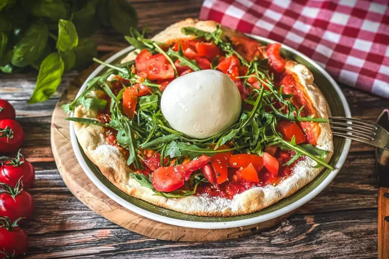 Pizza mit frischen Tomaten, Rucola und einer Kugel Burrata, die Lust auf burrata selber machen macht.