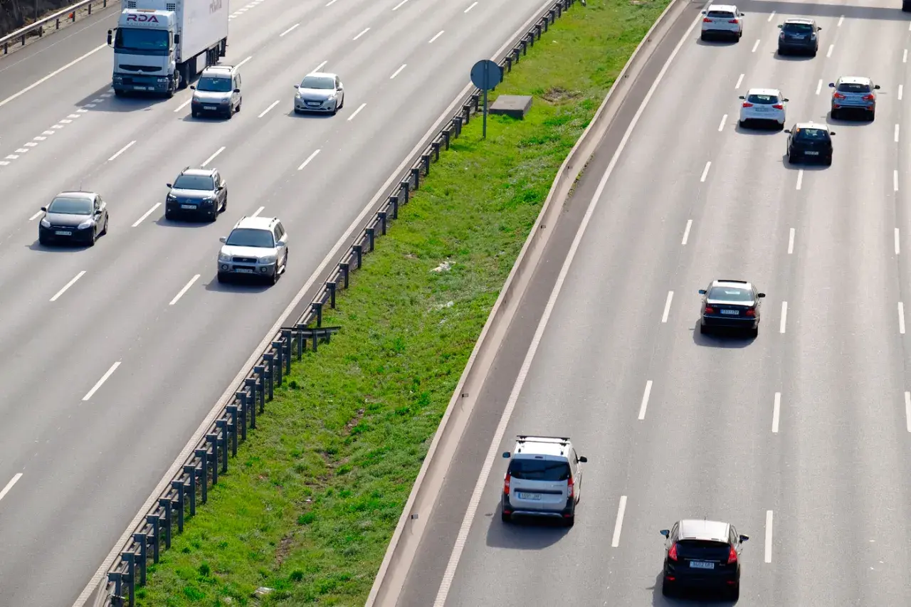 Varios coches circulan por la autopista. Un camión blanco lidera el tráfico. ¿Es correcto este adelantamiento?