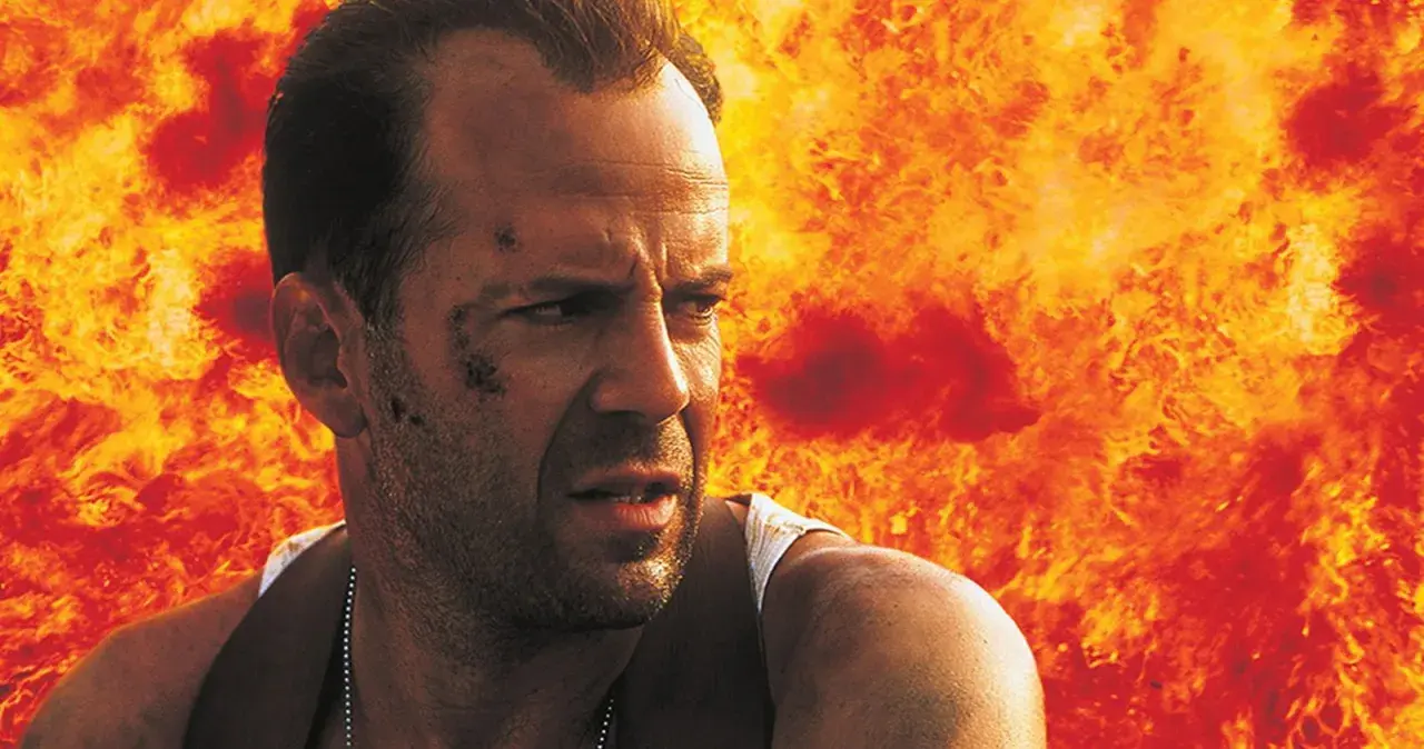 Bruce Willis i en actionfylld scen, med eld bakom sig. En klassisk bild från filmer med Bruce Willis.