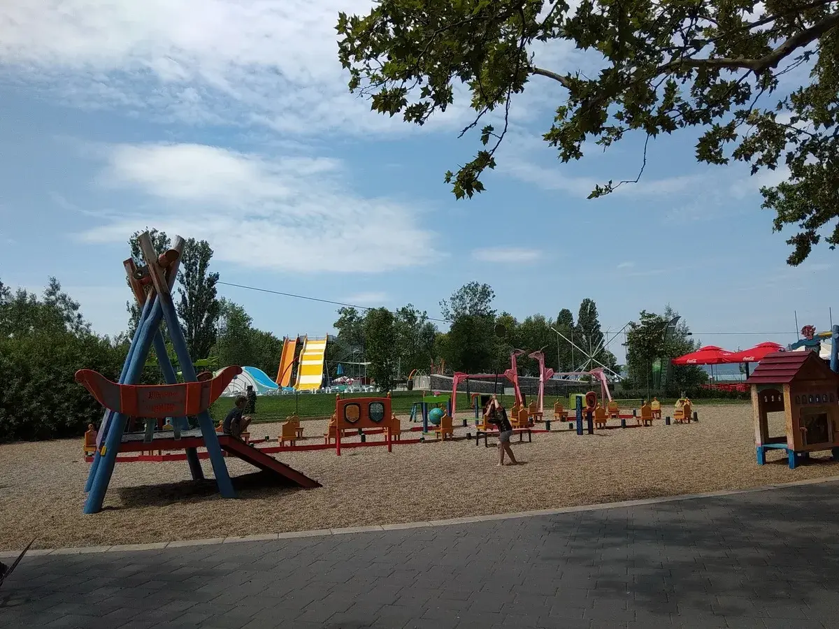Plac zabaw z atrakcjami dla dzieci nad Balatonem: zjeżdżalnie, huśtawki i domek.